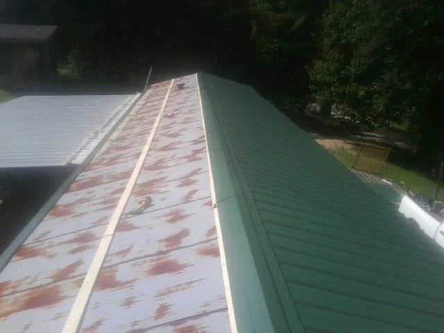 Old rusted panels beside newly installed green metal roofing — Wind Damage Roof Repair by Roofing Brothers in Abingdon