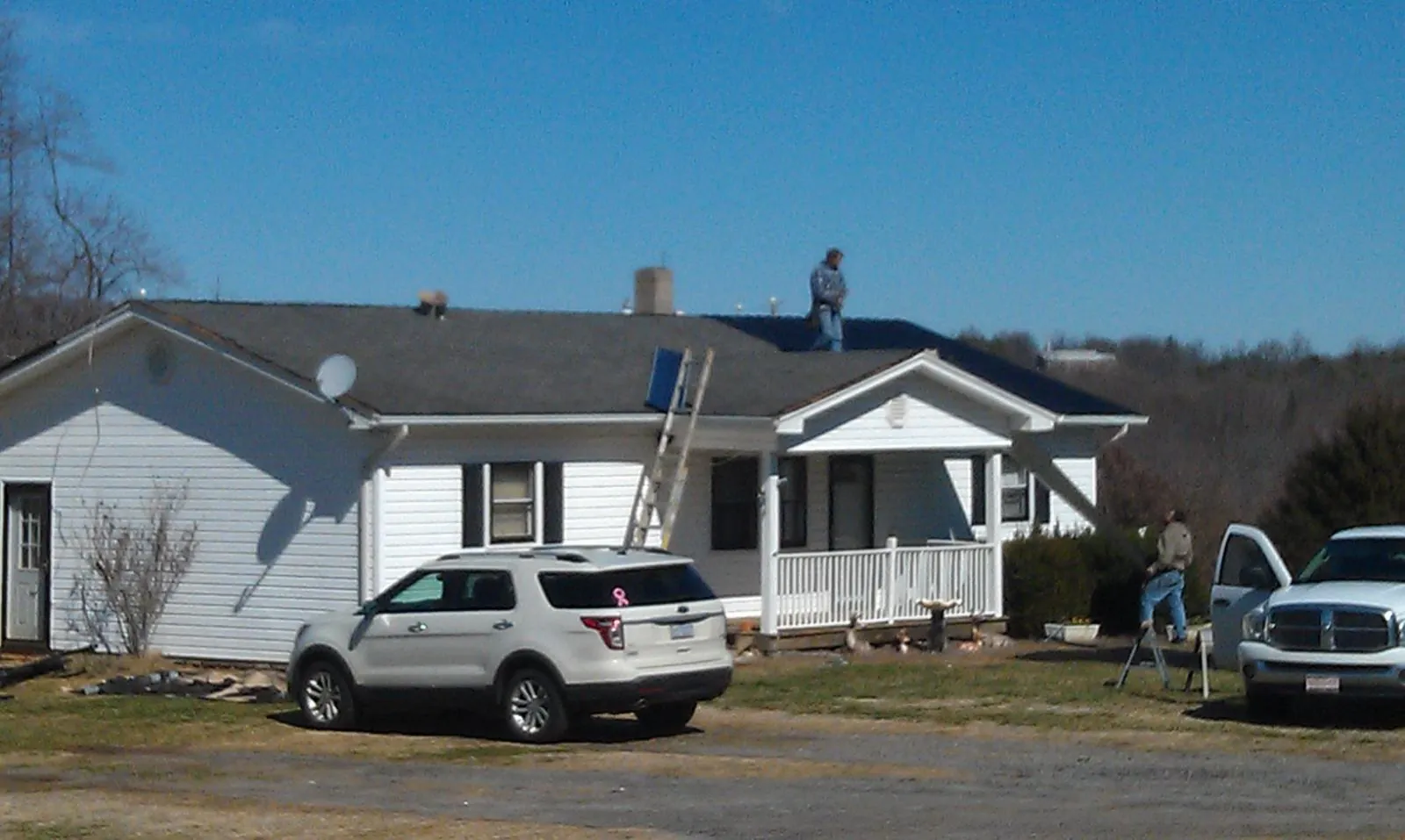 Roofers stripping shingles from a white ranch house roof in Abingdon
