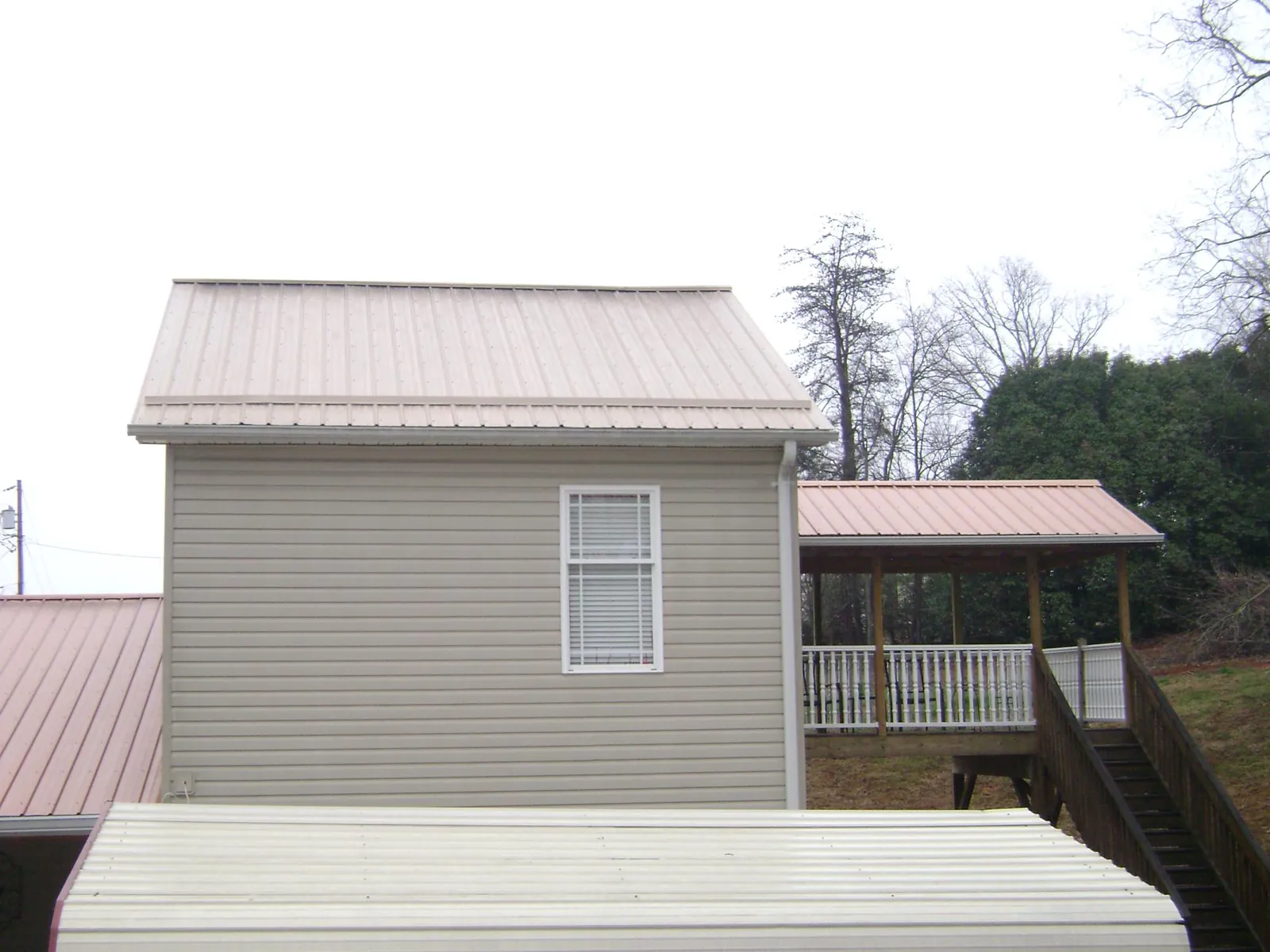 Tan metal roofs on a two story addition and attached porch, from a Roof Replacement job in Abingdon